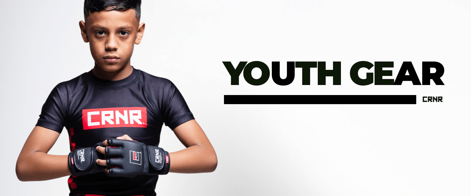 Photo a youth athlete wearing Combat Corner Youth and Kids Gear. The boy is wearing Combat Corner Youth Rash Guard, MMA Spar Gloves, and Fight Shorts.